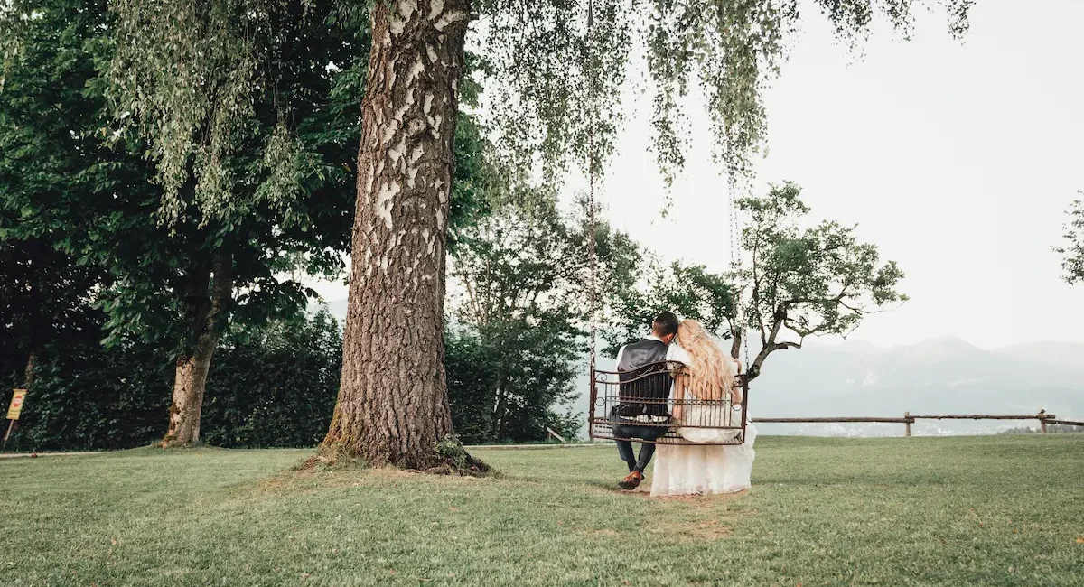 Brautpaar sitzt gemeinsam auf Schaukel in Naturkulisse