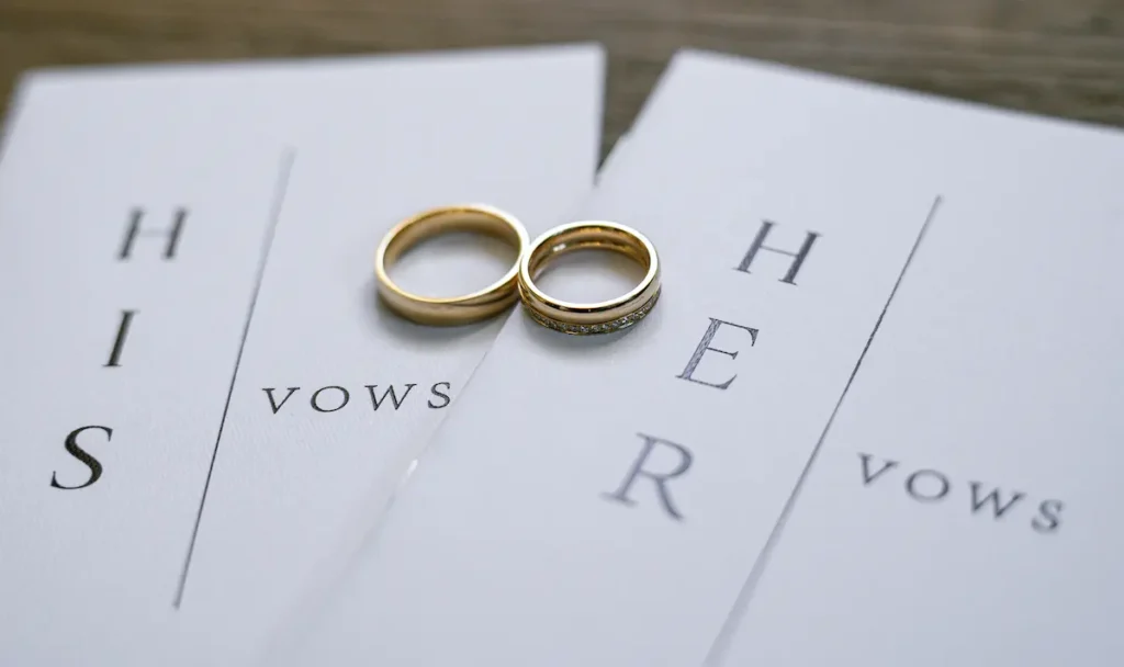 Eheringe liegen auf gedruckten Ehegelübden bei einer Hochzeit.