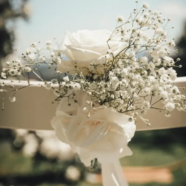 Blumendeko mit weißen Rosen und Schleierkraut an einem Traustuhl bei einer freien Trauung