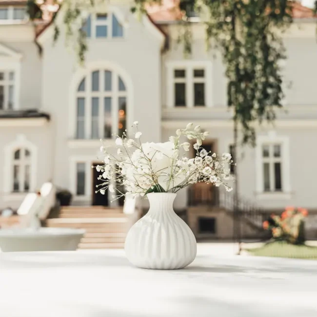 Weiße Blumenvase als Hochzeitsdekoration vor eleganter Villa