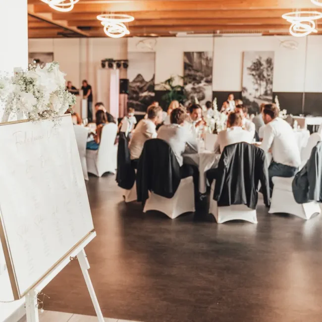 Hochzeitsgesellschaft sitzt an festlich gedeckten Tischen im modernen Hochzeitssaal bei einer Feier in Österreich