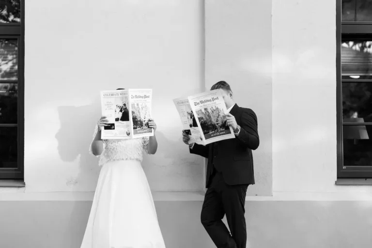 Braut und Bräutigam posieren humorvoll mit Zeitung bei modernem Hochzeitsshooting.